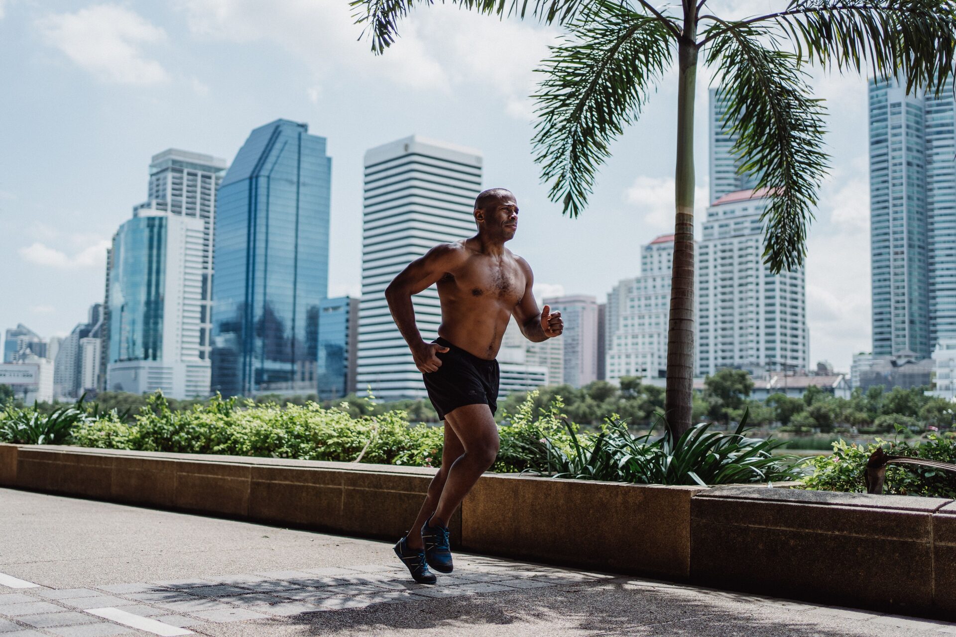 A runner mid-stride on a city path, working hard and in control, shot from the side.