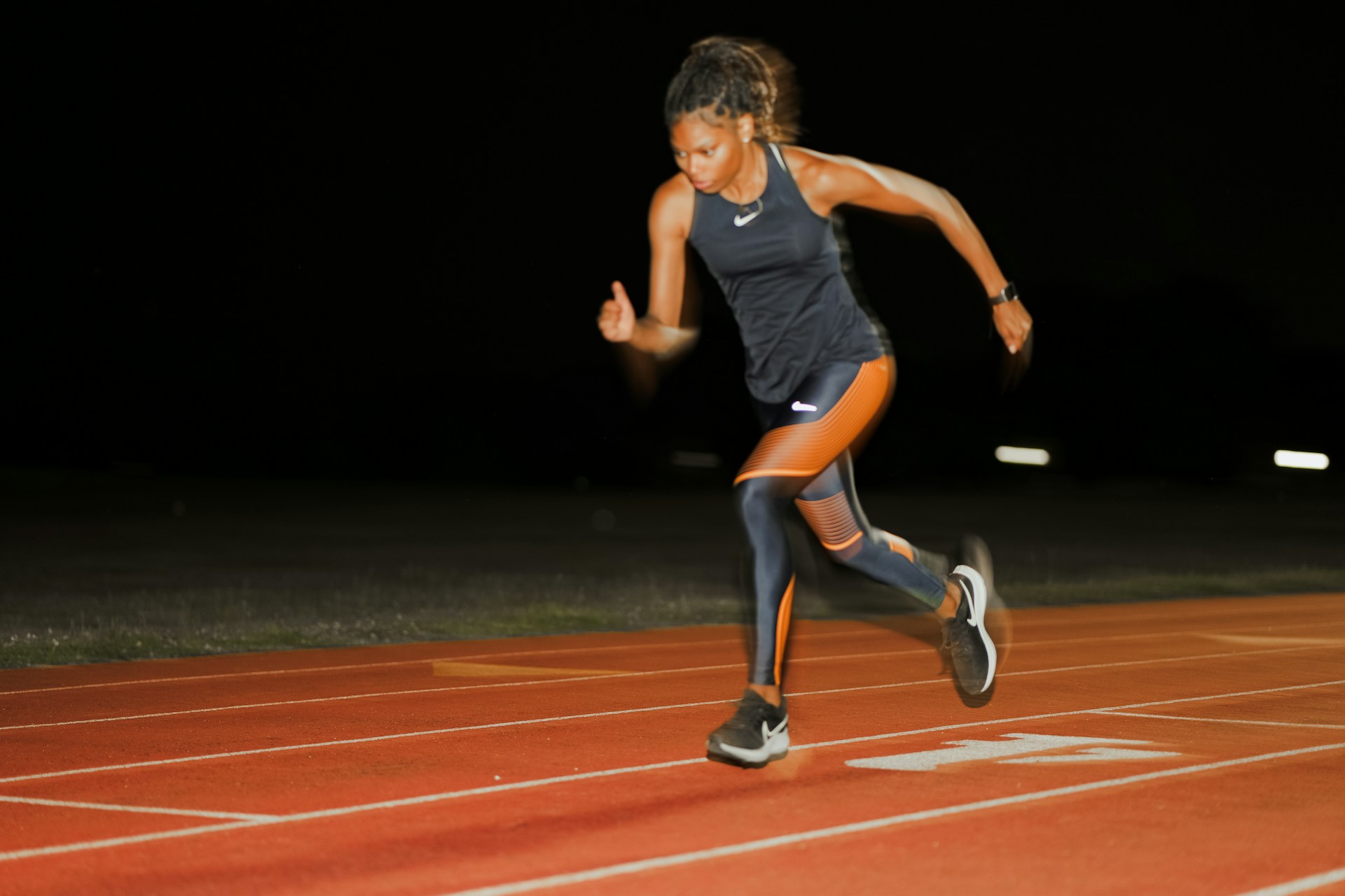 Runner doing intervals on a track at dusk.